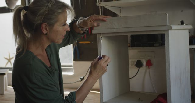 Woman Assembling Furniture Piece with Screwdriver in Workshop - Download Free Stock Images Pikwizard.com