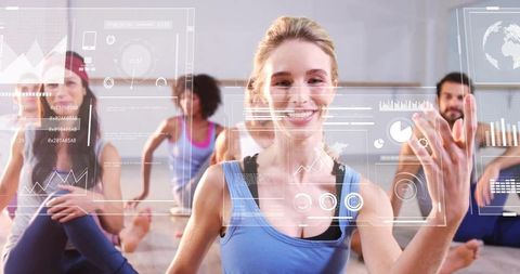Smiling woman reaching toward holographic fitness HUD during group yoga class