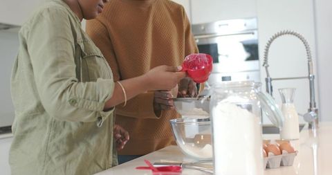 Couple sifting flour together at modern kitchen island for home baking and togetherness
