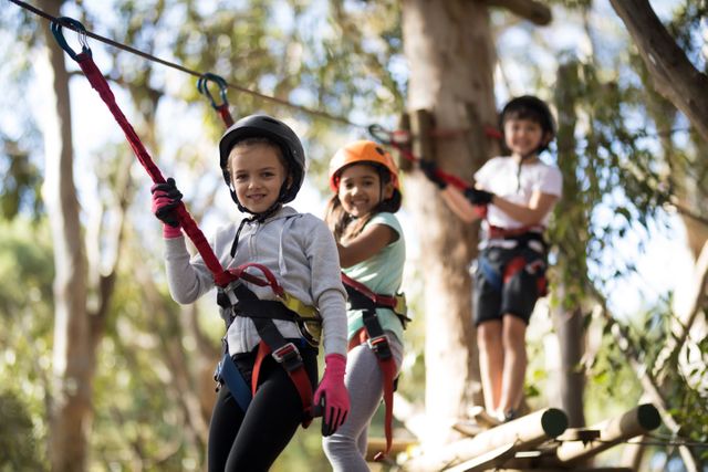Children having fun on a zip line in a forest, wearing helmets and safety gear. Perfect for illustrating outdoor activities, adventure parks, childhood fun, and team-building exercises. Ideal for use in advertisements, brochures, and websites promoting outdoor recreation and family-friendly activities.