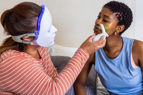 Diverse women using led facial device at home for glowing skin and skincare treatment