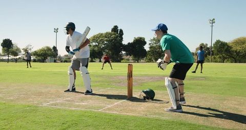 Youth cricket match showing batsman playing shot with wicketkeeper ready and fielders backing