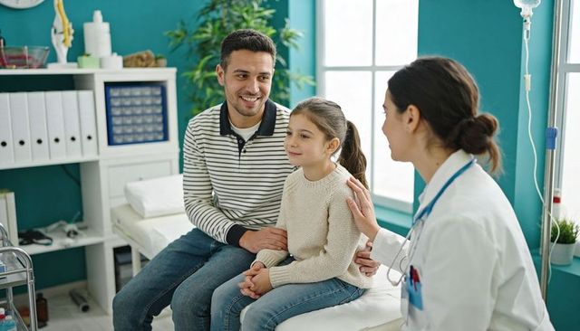 Father and daughter during reassuring pediatric checkup with friendly female doctor