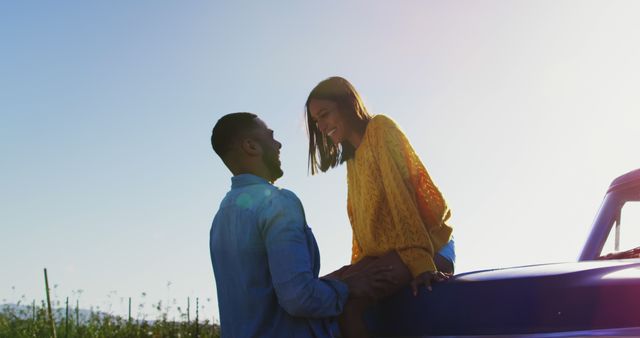 African American couple enjoys a sunset outdoors, with copy space. They share a romantic moment beside their car in a serene field.