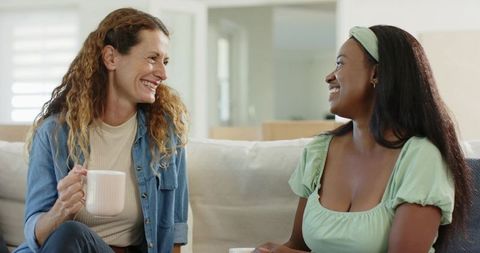 Smiling Friends Sharing Relaxing Coffee Time on Comfortable Sofa