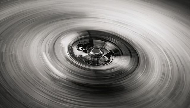 Spinning vinyl record with reflective metal spindle and circular motion blur