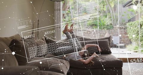Reclining girl using tablet on sectional sofa with augmented reality interface overlays