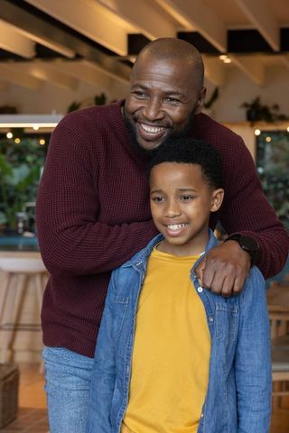 Warm african american father embracing son in cozy kitchen smiling family portrait