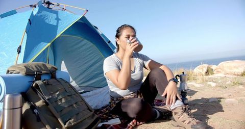 Asian Woman Enjoying Morning Drink at Coastal Campsite