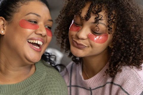 African american friends laughing wearing red hydrogel eye patches cozy closeup bonding