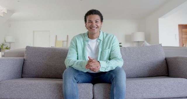 Smiling Young Man Sitting on Couch at Home in Bright Living Room - Download Free Stock Images Pikwizard.com