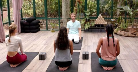 Group meditation yoga session in tranquil studio with glass walls