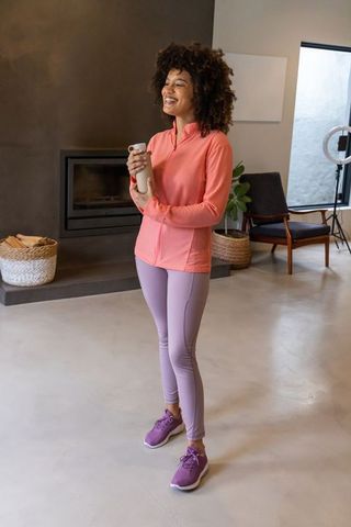African american woman holding water bottle smiling in modern minimalist living room