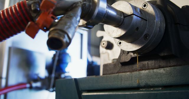 Close-up of a metalworking lathe machine tool with a sharp cutting tool, capturing the precision of the manufacturing process. This industrial equipment is essential for shaping metal parts in workshops and factories.