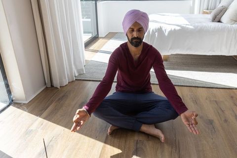 Turban-clad man meditating peacefully in bright bedroom
