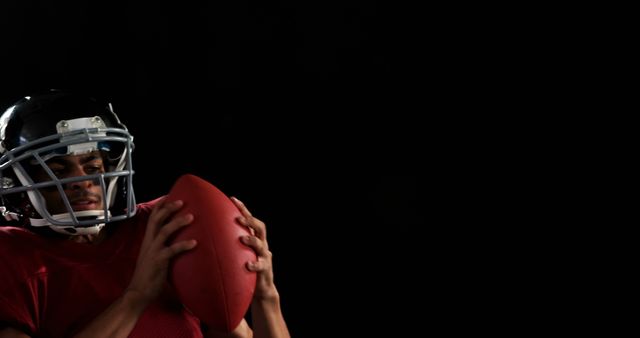 Football Player Holding Ball in Dim Lighting on Black Background - Download Free Stock Images Pikwizard.com