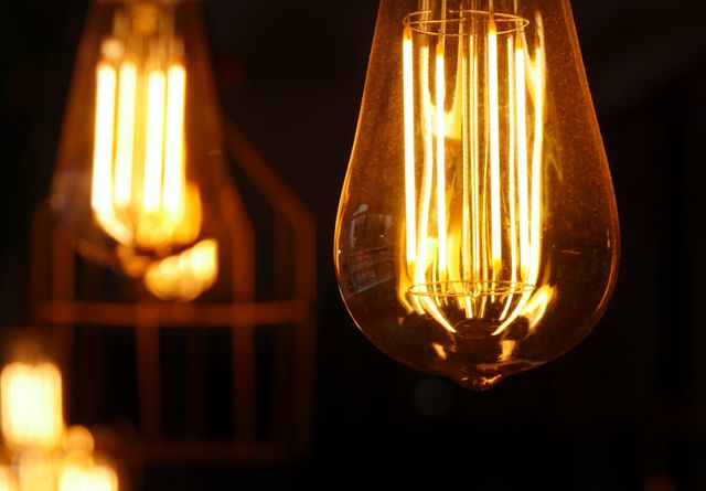 Close-up view of glowing vintage Edison light bulbs, showcasing intricate filament design and warm light. Perfect for use in articles or promotional materials about interior design, lighting solutions, energy efficiency, or retro aesthetics.