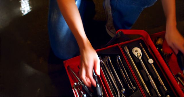Mechanic organizing tools in a red toolbox, including various wrenches and repair equipment. Ideal for use in repair, maintenance, workshop, and automotive industry presentations or DIY projects.