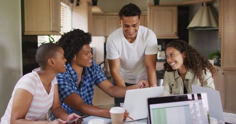 Diverse friends working together in home kitchen with laptops