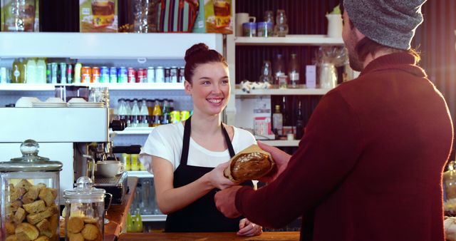 Friendly barista smiling while handing fresh bread to customer across counter in coffee shop. Perfect for illustrating customer service, bakeries, small businesses, and friendly interactions between staff and customers.