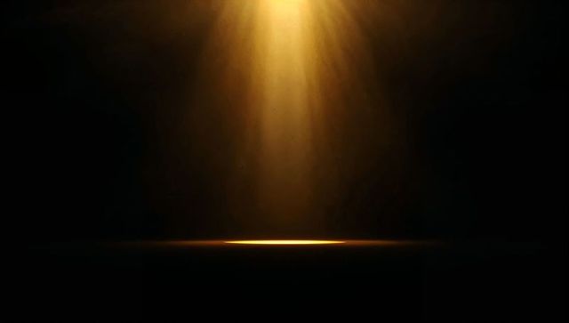 Warm golden spotlight casting narrow beam on dark studio floor revealing dust particles
