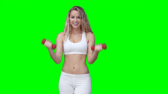 Woman engaged in a workout holding red dumbbells, wearing fitness attire. Appears against a green screen, suggesting an adaptable visual for health and fitness promotions, personal training advertisements, or website graphics. Ideal for concepts related to exercise guides, gym appeals, and active lifestyle editorial.