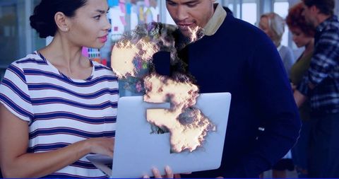 Burning laptop collaboration concept showing team reacting to data breach in open-plan office