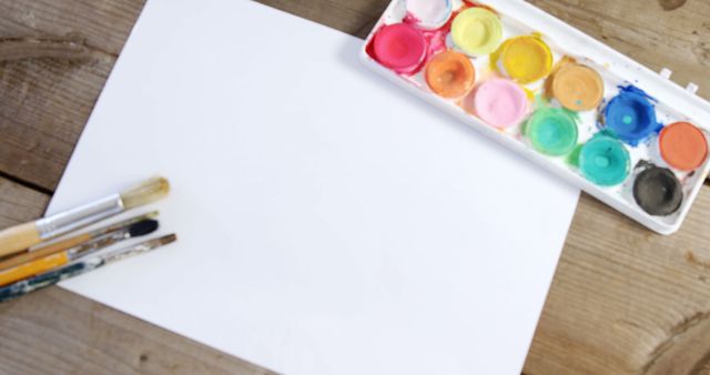 Watercolor paint and paintbrushes with canvas on wooden background - Download Free Stock Photos Pikwizard.com