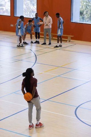 Player Ready for Action While Team Huddles with Coach in Gym