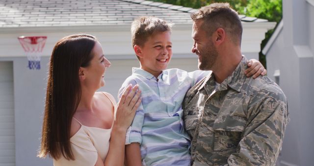 Happy caucasian male soldier embracing his smiling son with wife in garden outside their house. soldier returning home to family.