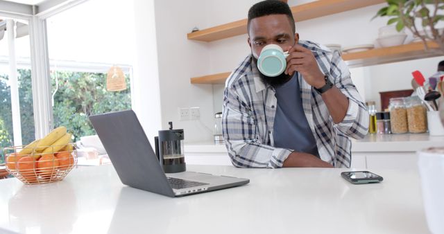 Man Drinking Coffee While Using Laptop in Modern Kitchen - Download Free Stock Images Pikwizard.com