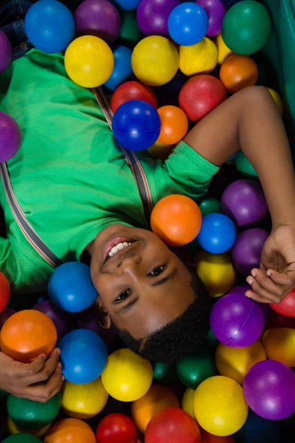 Overhead view of happy boy playing in ball pool during party