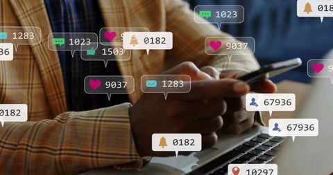 Man checking social media notifications on smartphone over laptop with floating badges