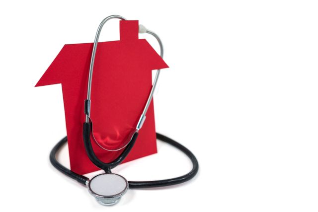 Stethoscope draped over red house cutout symbolizing home healthcare services. Ideal for illustrating concepts related to home medical care, healthcare services, and health check-ups at home. Useful for medical websites, healthcare brochures, and home care service promotions.