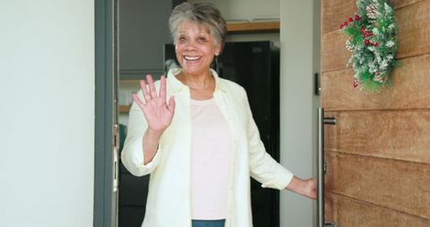 Cheerful Senior Woman Greeting with Holiday Wreath