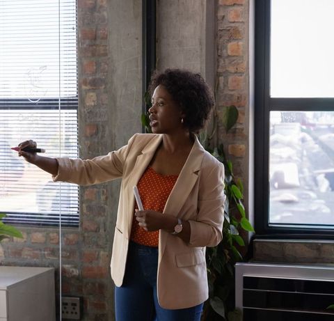 African american woman presenting strategy on glass partition in urban loft office