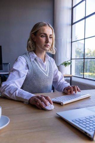 Professional Woman Focused Working at Office Desk by Window