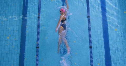 Female Swimmer Performing Backstroke in Lap Pool Wearing Pink Cap Overhead Action
