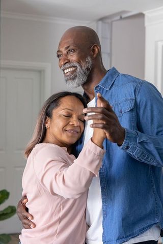 Mature african american couple dancing slowly at home embracing romantic moment