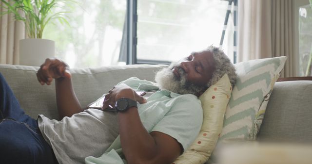 Senior man relaxing on a couch, taking a nap with a content expression. Ideal for concepts of relaxation, home comfort, restful living, healthy aging, peaceful moments, and leisure time. Perfect for advertisements, lifestyle blogs, retirement living promotions, and healthcare materials.