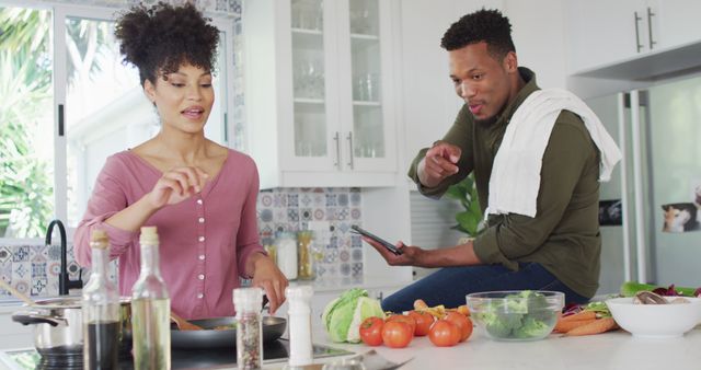 Happy african american couple cooking and using tablet in kitchen. Spending quality time at home together concept.
