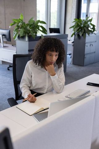 Focused professional woman writing notes at office desk