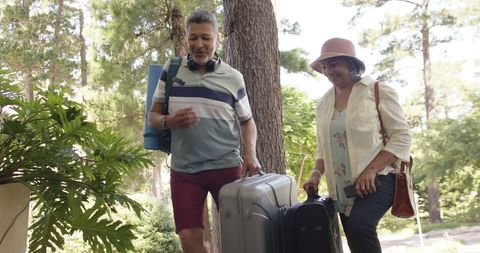 Senior Couple Arriving at Forest Retreat with Luggage