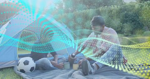 Family camping with dad pouring coffee, son holding mug, digital connectivity overlay