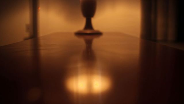 Warm low-light polished wood table reflection with lamp bokeh, grain and cozy warmth