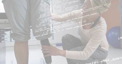 Physical therapist adjusting below-knee prosthesis while patient stands in rehab