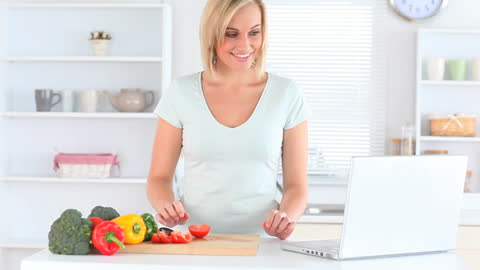 Woman Preparing Meal Using Laptop in Modern Kitchen