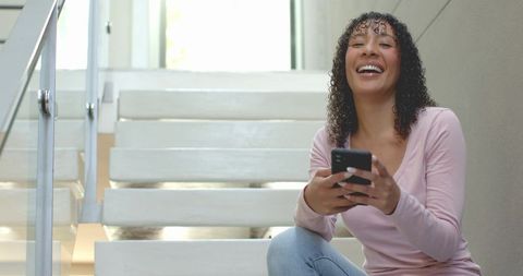 Young Woman Relaxing on Stairs Holding Smartphone