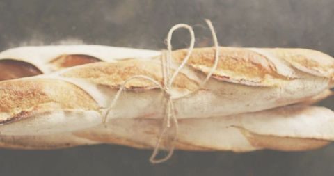 Displaying rustic french baguettes tied with twine on dark tabletop, flour-dusted crust