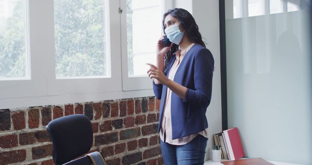 Businesswoman Wearing Face Mask Talking on Phone Standing in Office - Download Free Stock Images Pikwizard.com